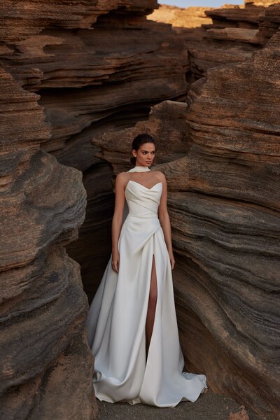 Das Brautkleid Danessa von Milla Nova Braut posiert in dem Brautkleid Danessa von Milla Nova vor einer Felswand